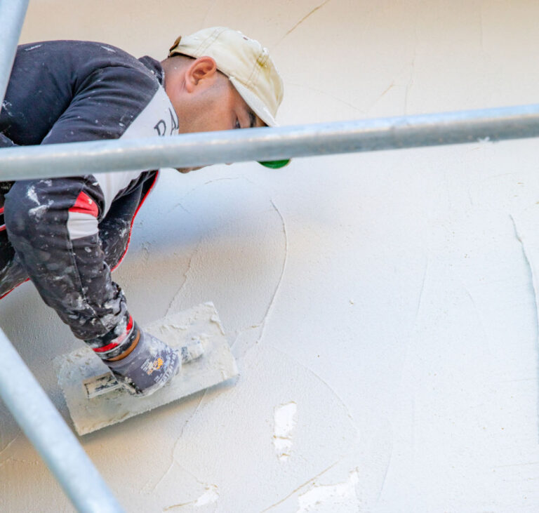 ouvrier appliquant un enduit sur une façade